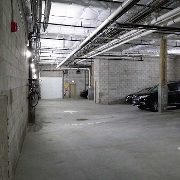 a parking garage with a bicycle and two cars.